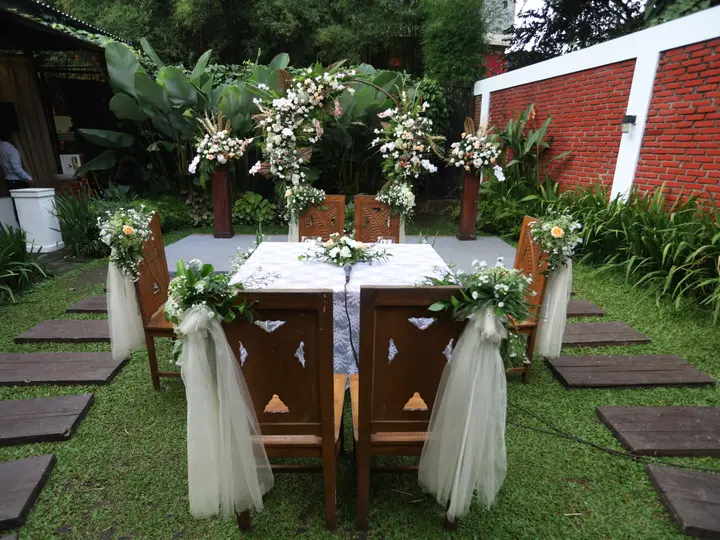 Set meja akad nikah berhias bunga segar di taman outdoor Kanaya